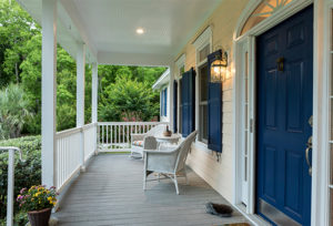 Chairs on front porch deck with lights on and blue shutters